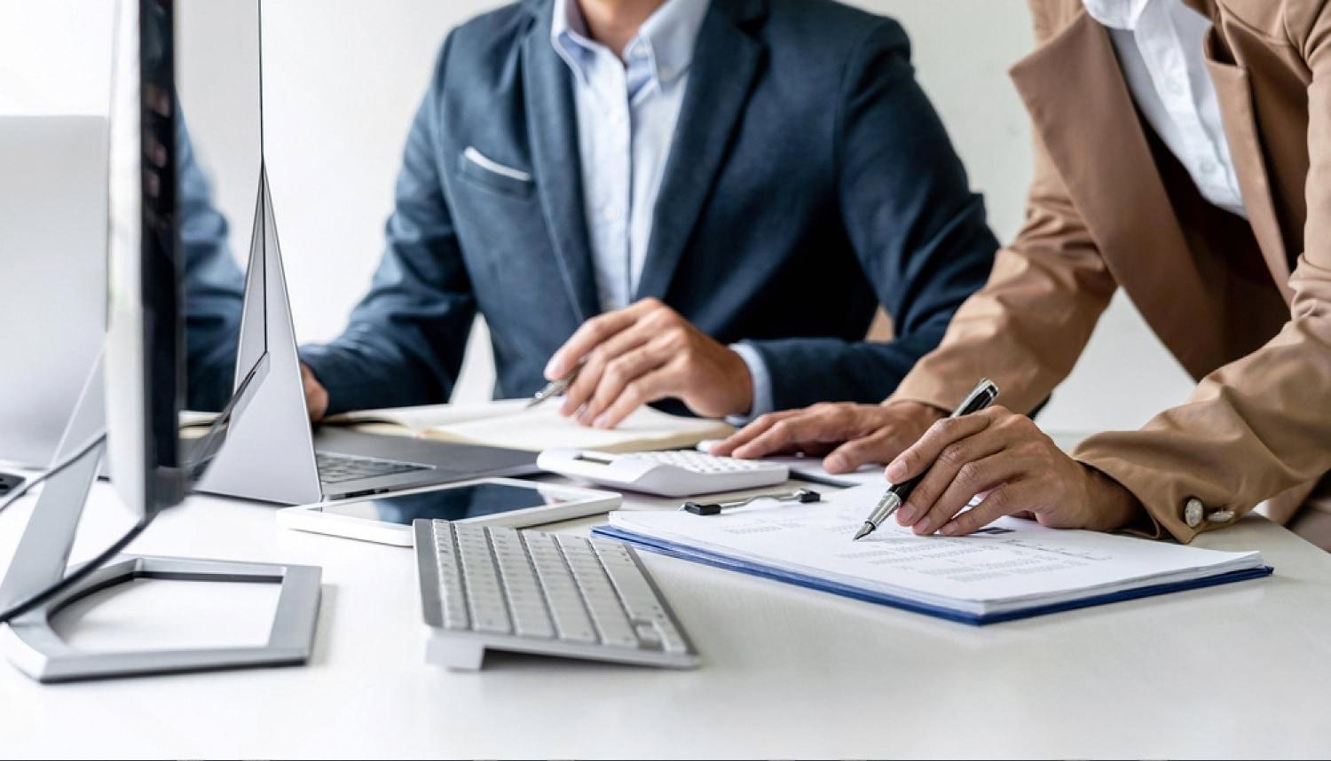 Two business partners reviewing international trade documents and financial reports at a desk