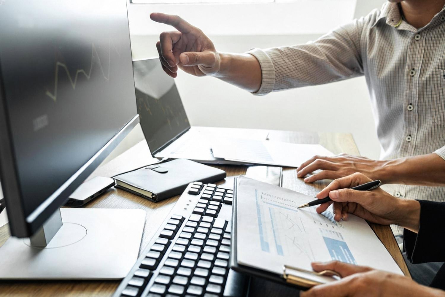 Compliance officer pointing at trade data on a screen during an export control review